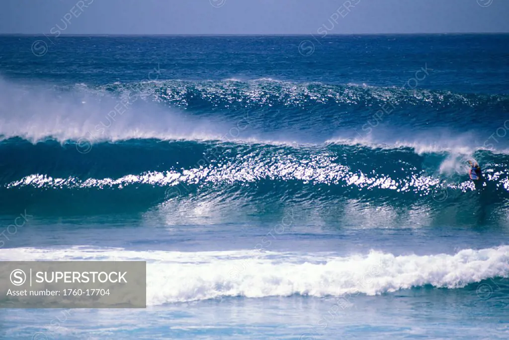Hawaii, Small body boarder in wave, shimmering sets, view from afar, wind spray