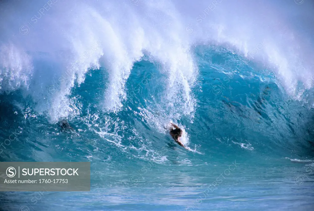 Oahu, Young man body surfing large cresting wave, spray on tips