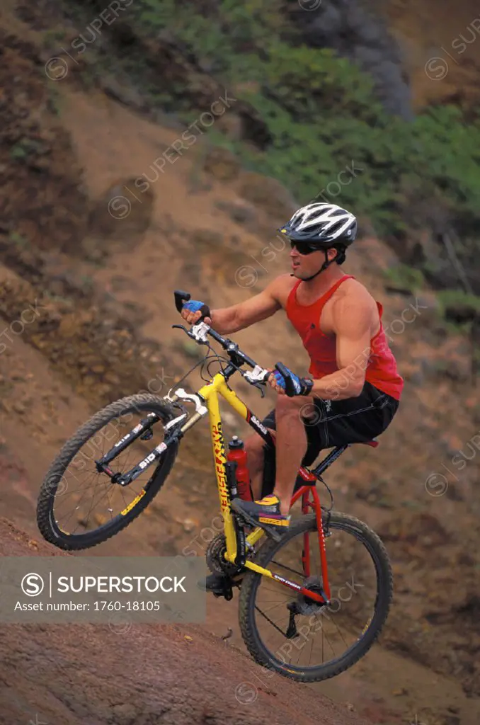 Hawaii, Maui, Nakalele Point, man mountain biking uphill, full length side view