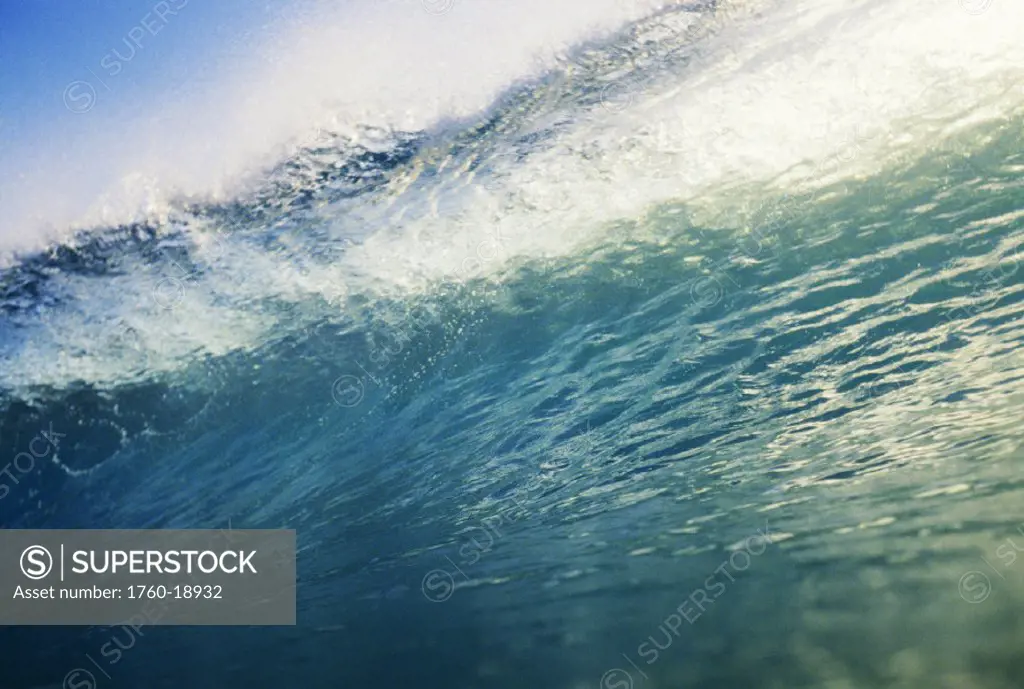 Translucent wave at it´s peak with white wash, blue sky.
