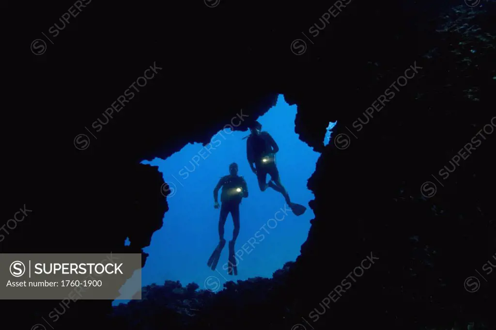Hawaii, Lanai, Two divers with flashlights, pictured at entrance to an underwater lava tube.