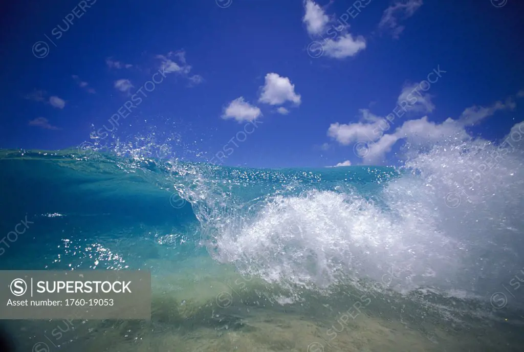 Curling turquoise wave, blue sky with small white clouds D1638