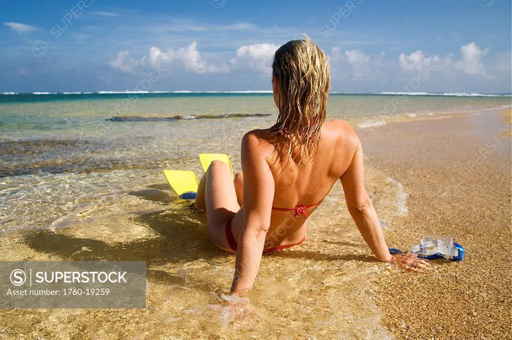 Hawaii, Kauai, Tunnels beach, A woman wearing yellow and blue fins on beach.