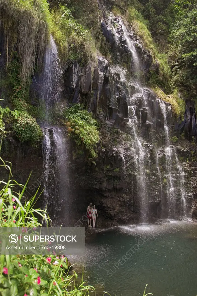 Hawaii, Maui, Hana Coast, couple at base of waterfall enjoying Blue Pool.