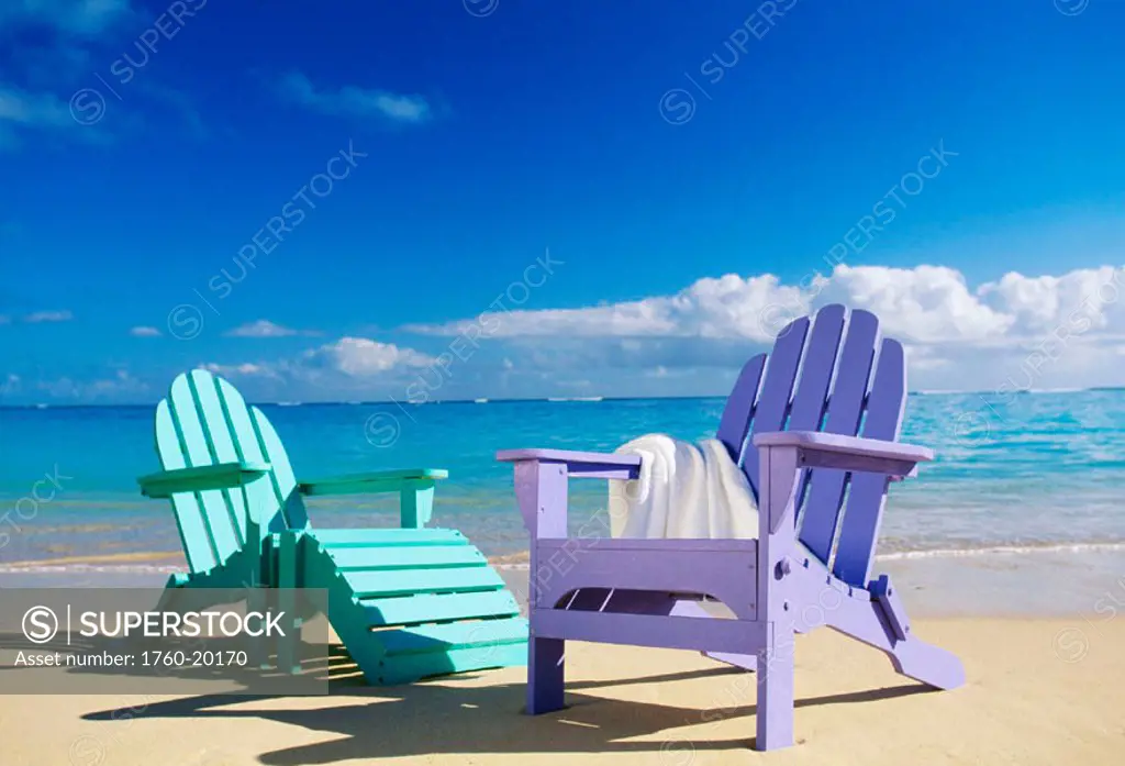 colorful beach chairs on beach, calm waves washing ashore turquoise water