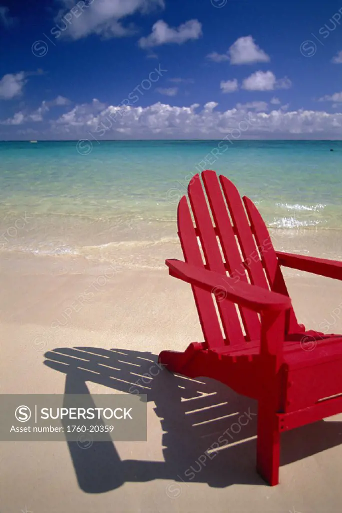 Front angle red wooden beach chair w/ shadow on beach, turquoise ocean D1715