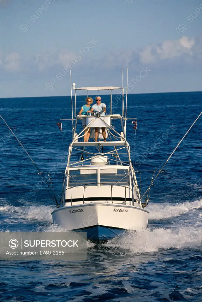Hawaii, front view of sport fishing boat, senior couple in flying bridge A14E