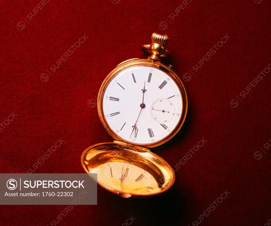 Image of gold pocket watch, laying on dark background