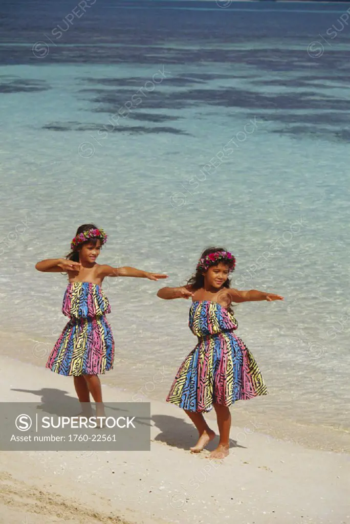 Two young girls with in hula dress dancing on the beach