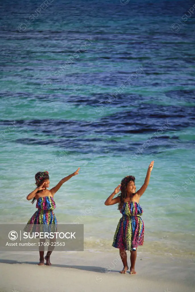 Two young girls with in hula dress dancing on the beach