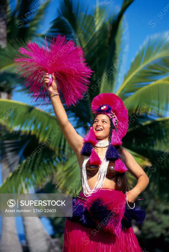 Tahitian dancer in colorful costume smiling, palm trees in background B1683