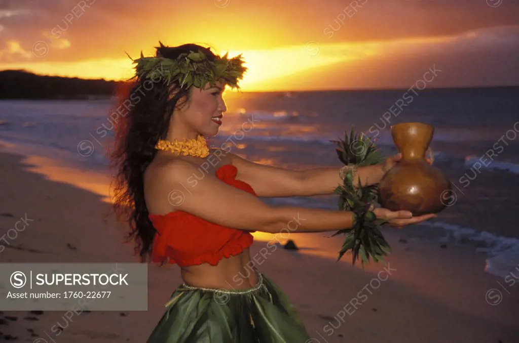 Side view of woman dancing at beach with ipu in hand, pink orange golden sunrise hues