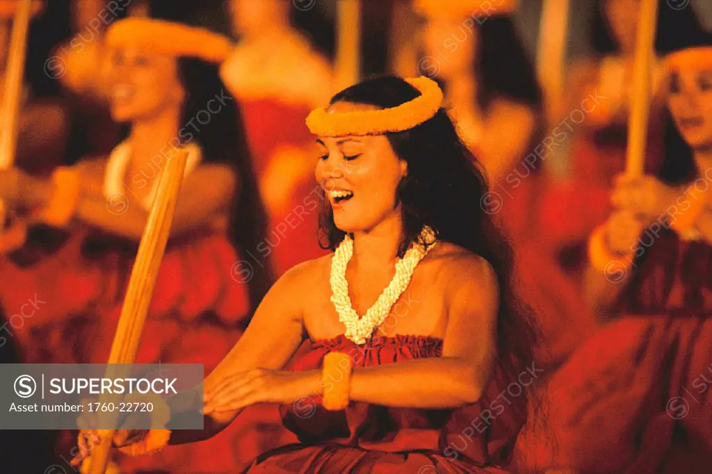 Hawaii, hula festival, women use sticks during performance reddish color background