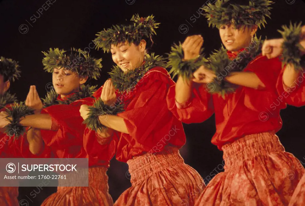 Hawaii, View of women wearing red, performing hula as a group on stage, nighttime
