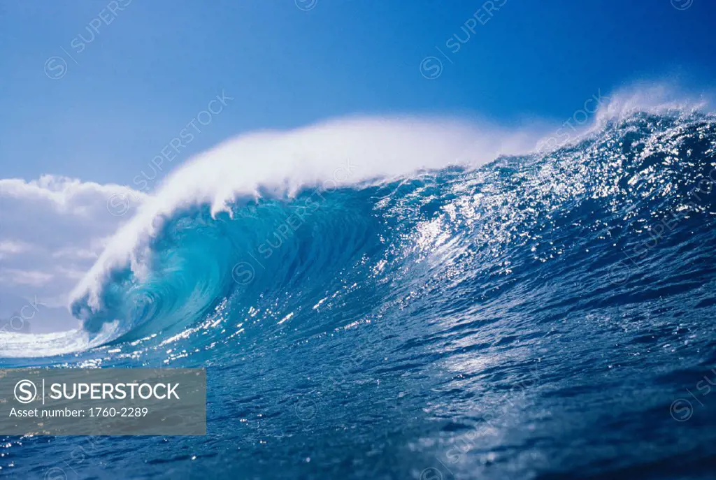 View of large, glassy wave, with blue sky in background