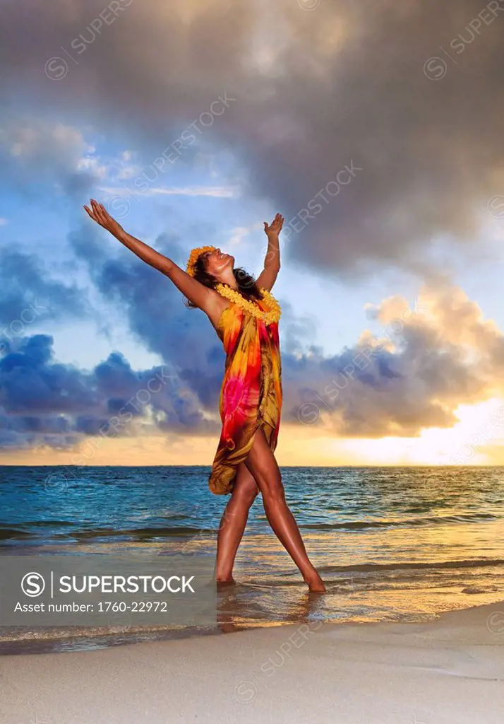 Hawaii, Oahu, Lanikai, Beautiful Hawaiian woman dancing hula on ocean shoreline.