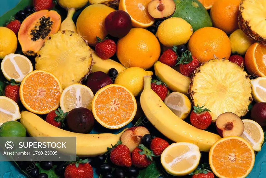 Mixed fruits with oranges, lemons, papaya and pineapple cut in half, banana & grapes