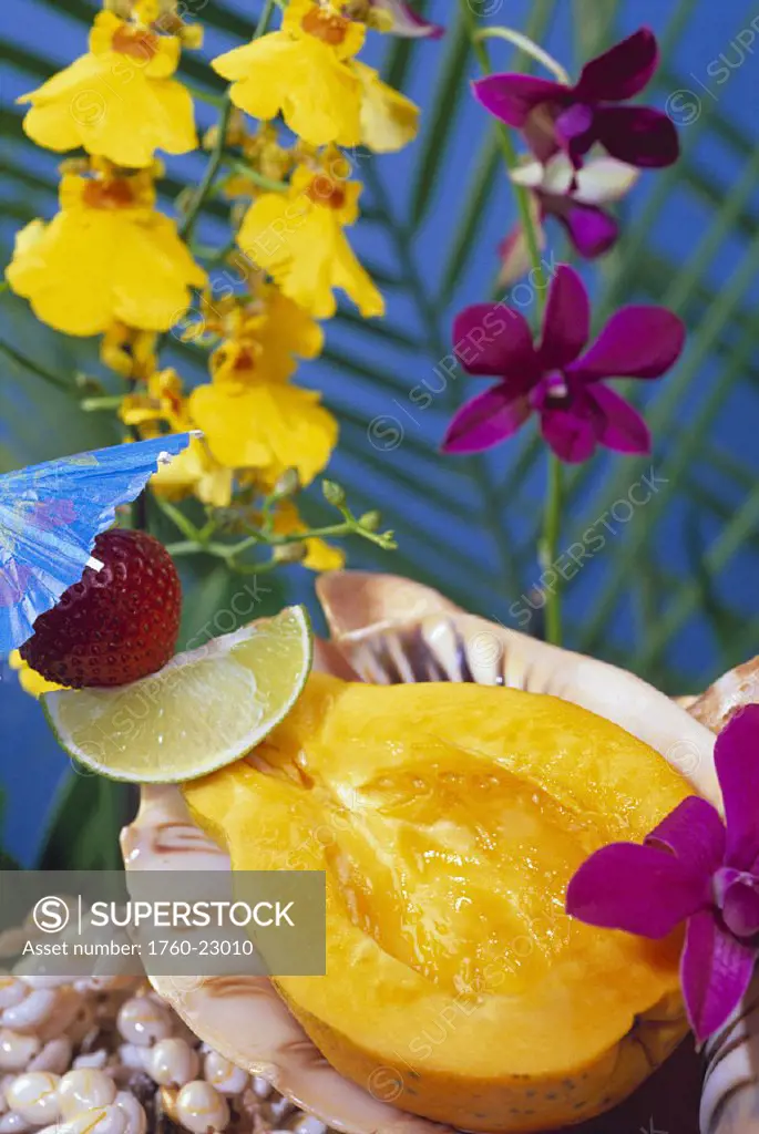Fresh half papaya served in shell strawberry lime garnish orchids background, colorful