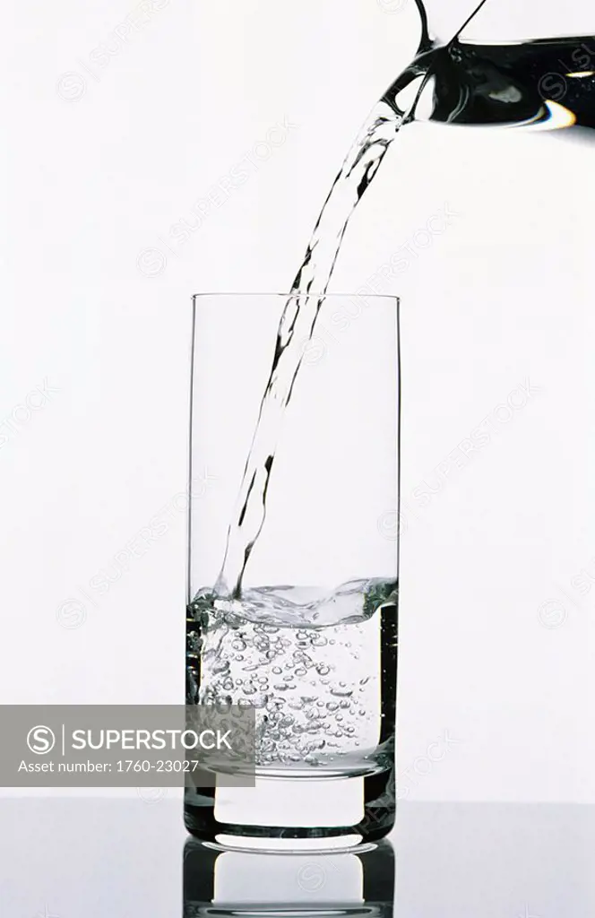 Water being poured from a pitcher into tall glass clear glass