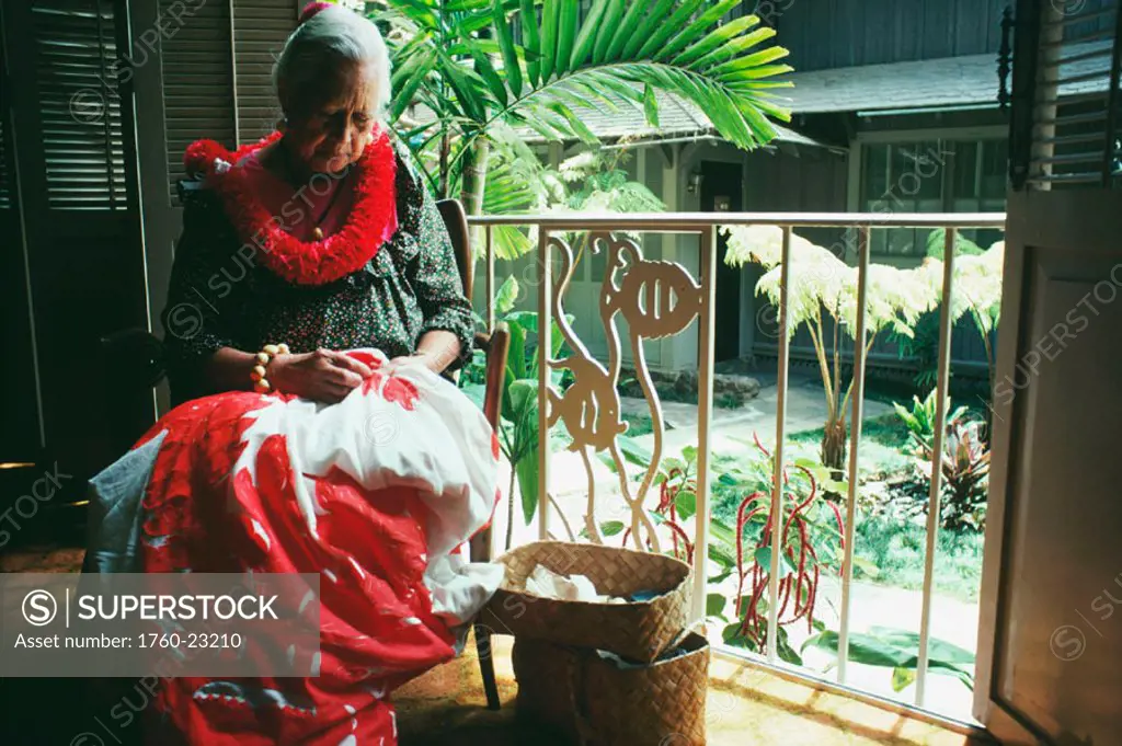 Elderly Hawaiian woman sits making a traditional Hawaiian quilt.