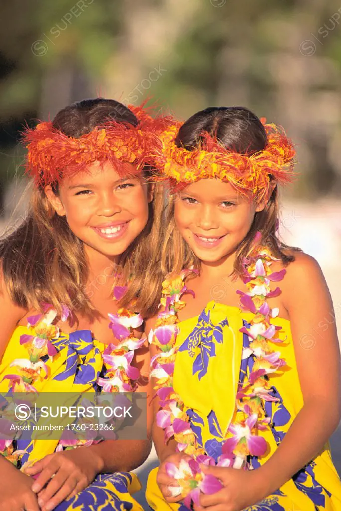 Two smiling local girls w/ haku, wearing colorful  pareo and lei