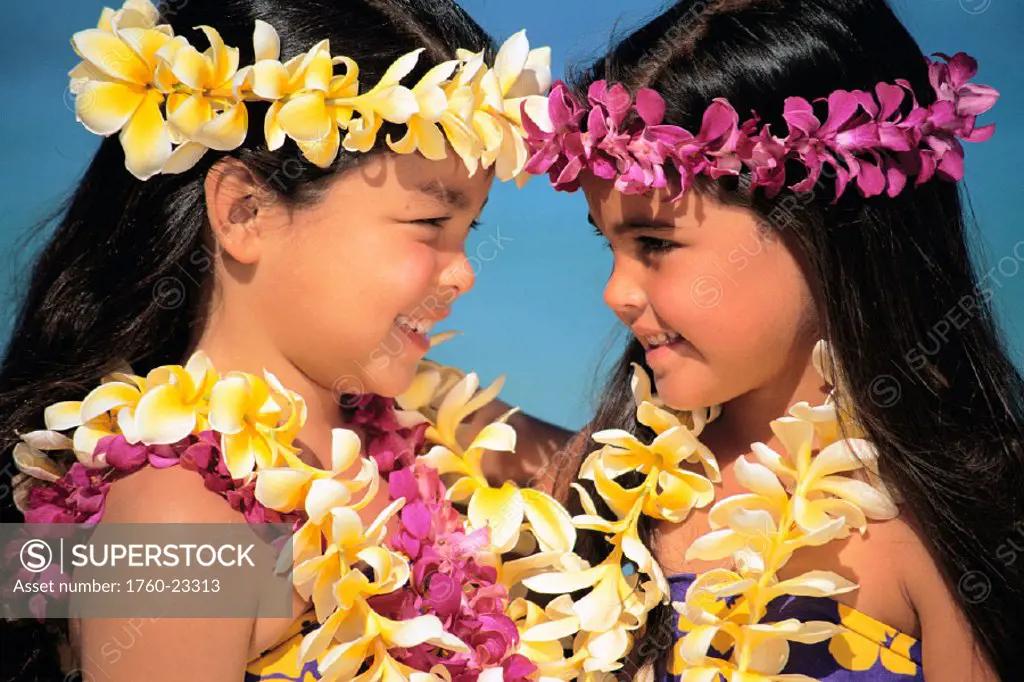 Closeup side view of two girls facing each other, plumeria & orchid leis