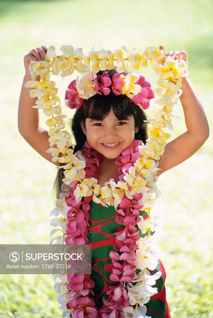 Smiling local girl wearing plumeria leis, holding another out in front