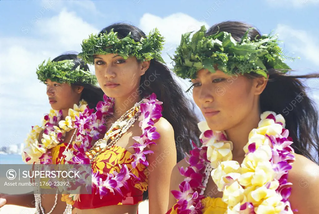 Three attractive young women wearing haku and variety of lei, outdoors