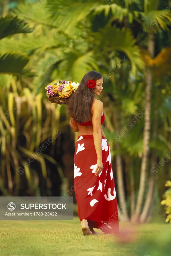 Polynesian woman walk outdoor wearing red pareo hold basket head turned, red hibiscus flower