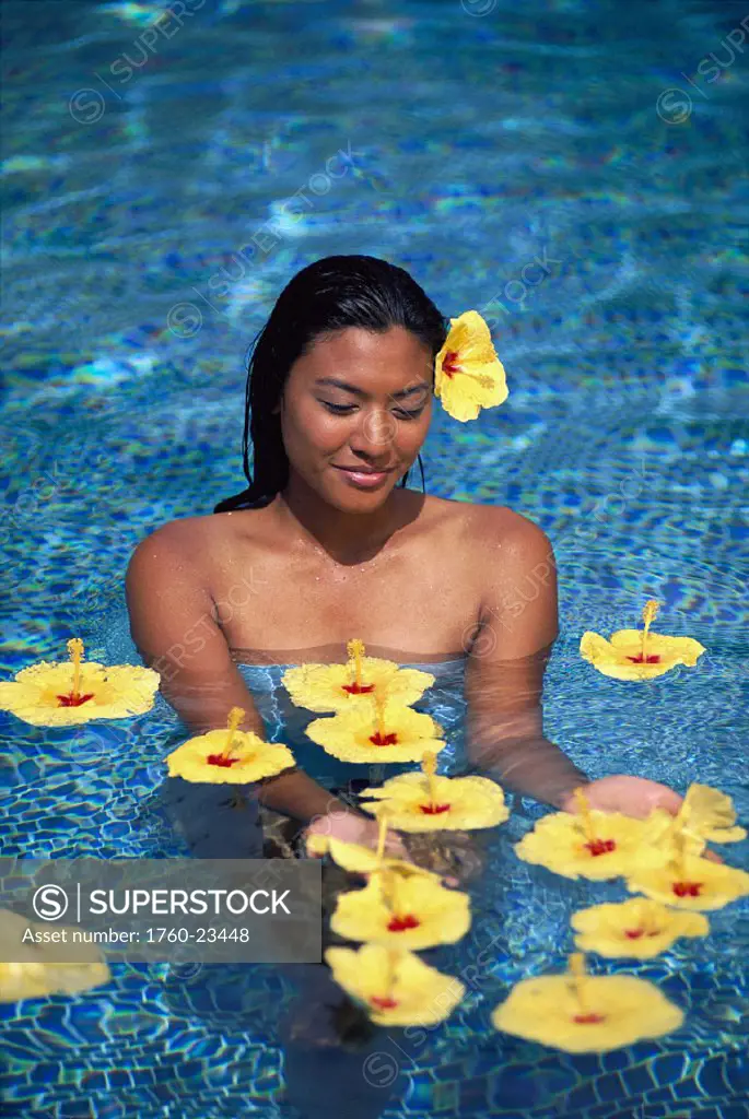 Local woman in water surrounded by tropical flowers, yellow hibiscus
