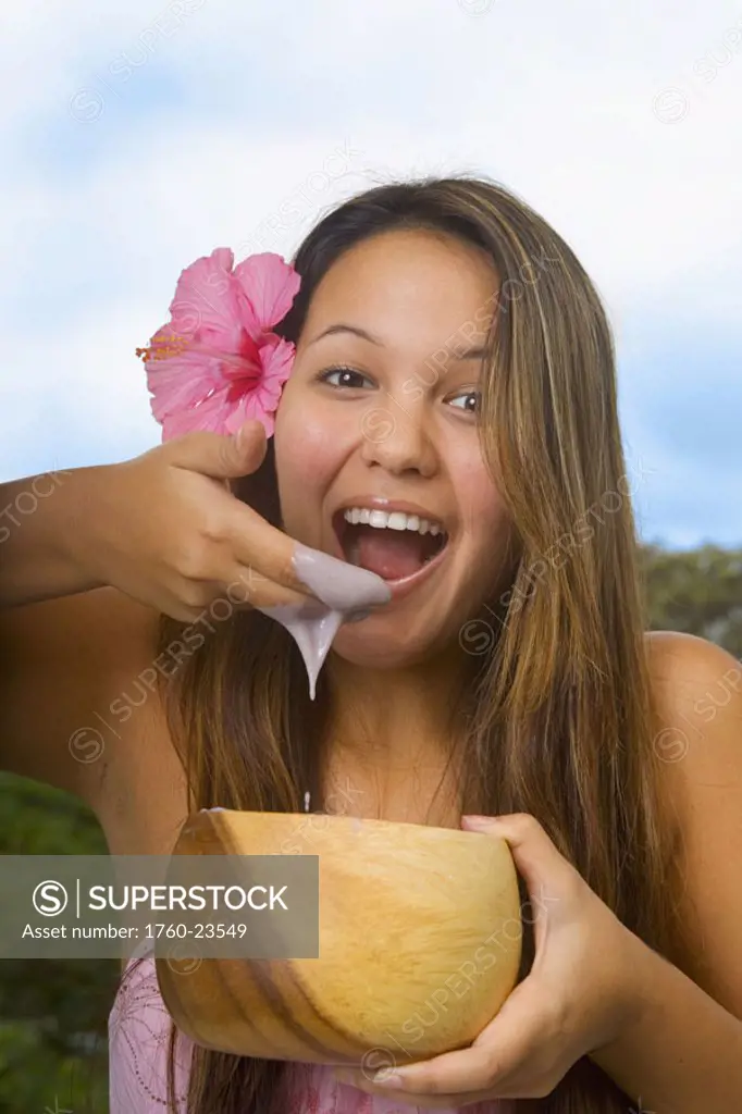 Hawaii, Girl eating poi with fingers out of wooden bowl.