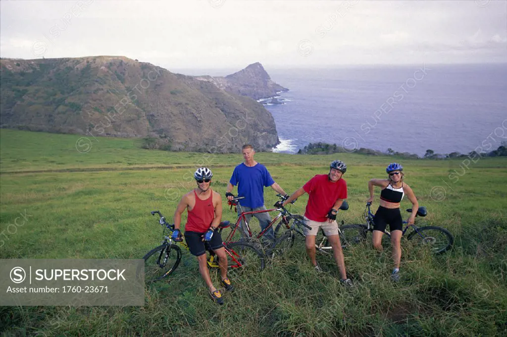 Maui near Kahakuloa group mountain bikers rest on side of road D1283 ocean bkgd scenic