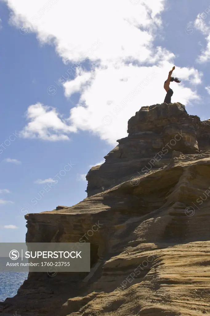 Hawaii, Oahu, young woman doing yoga on a cliff next to the ocean.