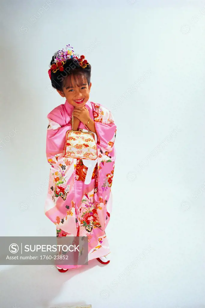 Asian girl in pink kimono holds purse to chest, full length, smiling studio shot