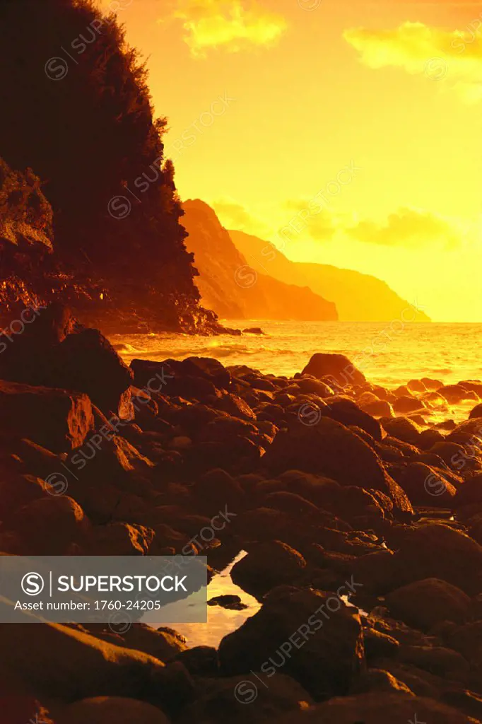 Hawaii, Kauai, NaPali Coast, sunset along rocky shoreline w/ tidepool, golden yellow sky