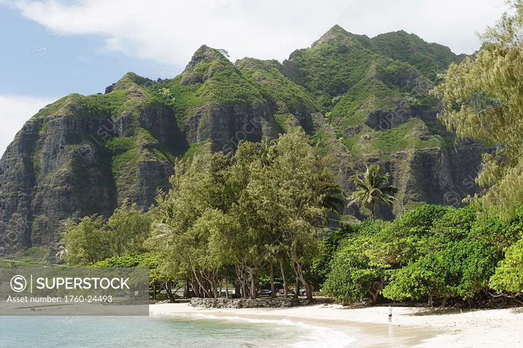 Hawaii, Oahu, Windward, Kahana, water washes onto sandy beach, lush mountains in background, cloudy sky