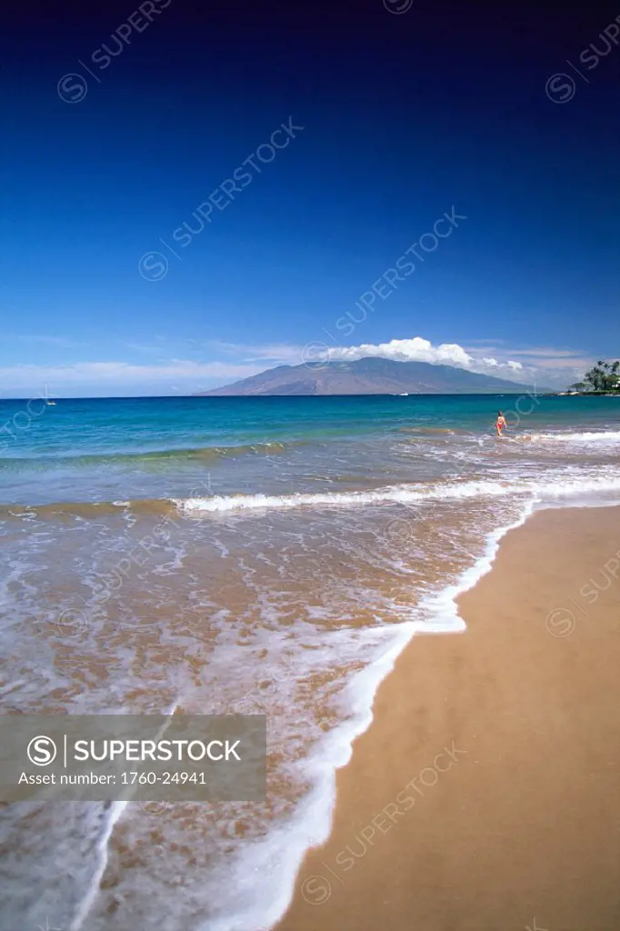 Hawaii, Maui, Wailea beach shoreline on a sunny day, woman in distance, mtns bkgd