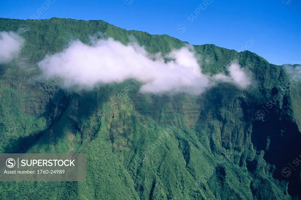 Hawaii, West Maui mtns from helicopter w/ cloud in front of green ridges, blue sky