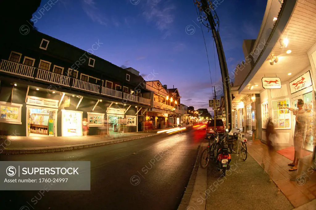 Maui, Lahaina, storefronts of Front Street at twilight, blurred car and people