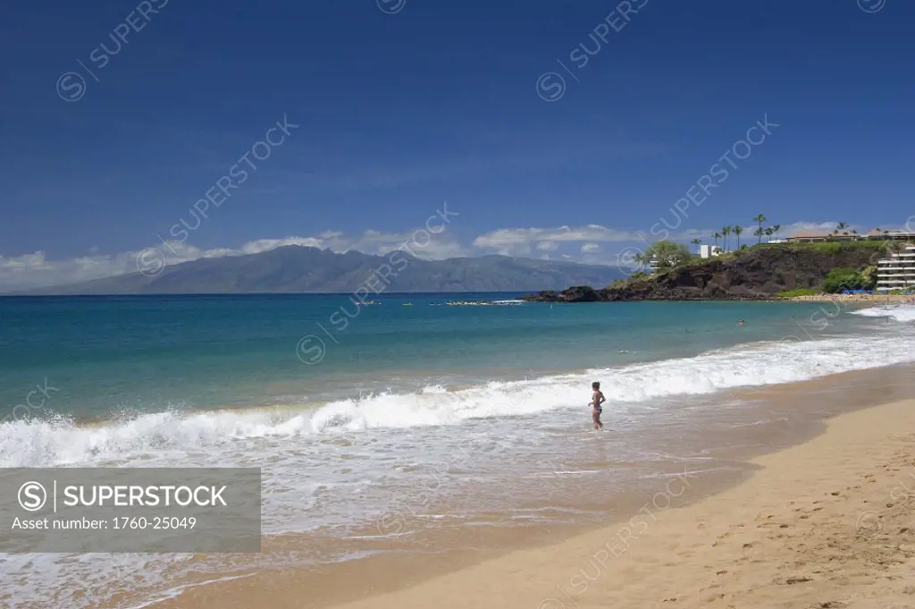 Hawaii, Maui, Kaanapali Beach, Black Rock and island of Molokai visible in distance, woman in surf.