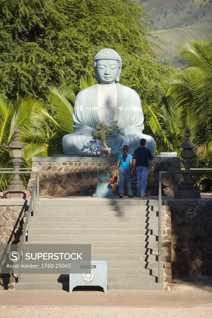 Hawaii, Maui, Lahaina Jodo Mission, Buddha statue, couple stand before it.
