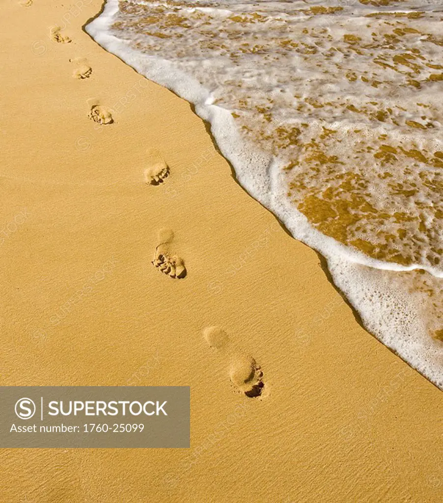 Hawaii, Maui, Makena State Park, Oneloa or Big Beach, Footprints in the sand along the ocean, golden light