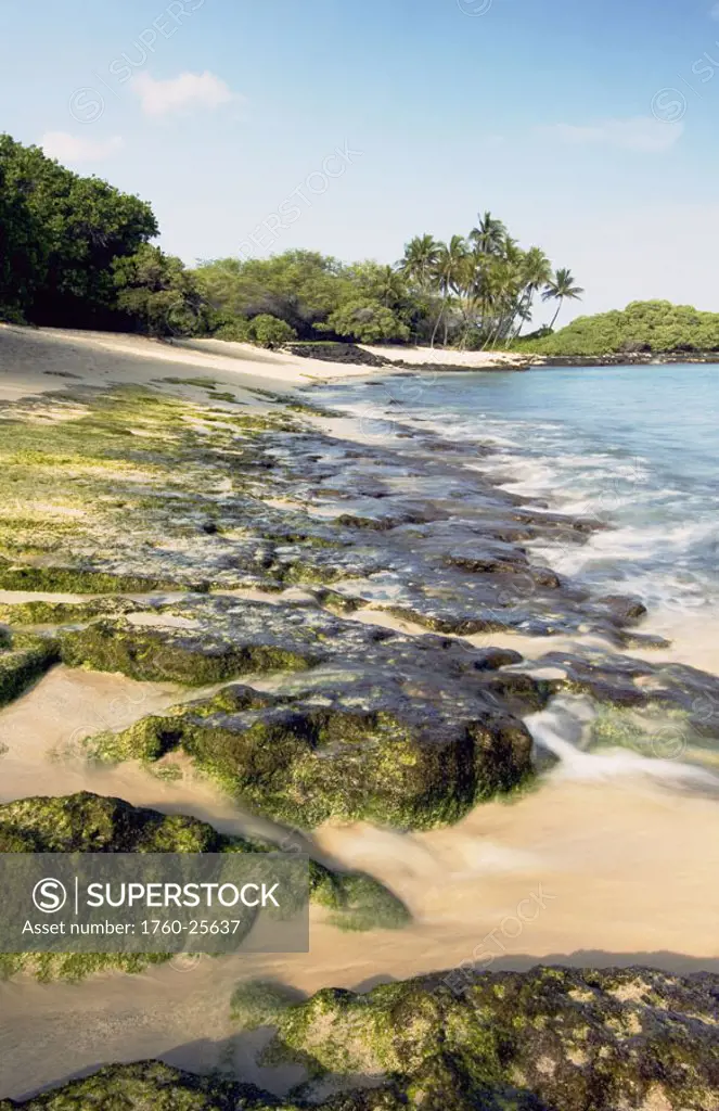 Hawaii, Big Island, North Kona, Mahaiula State Beach Park, White sand beach with mossy rocks along the shoreline.