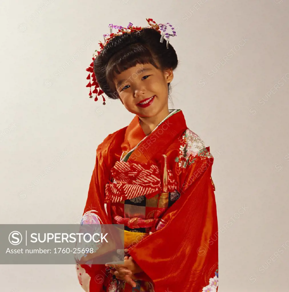 Smiling Japanese girl in red kimono, hands clasped in front.