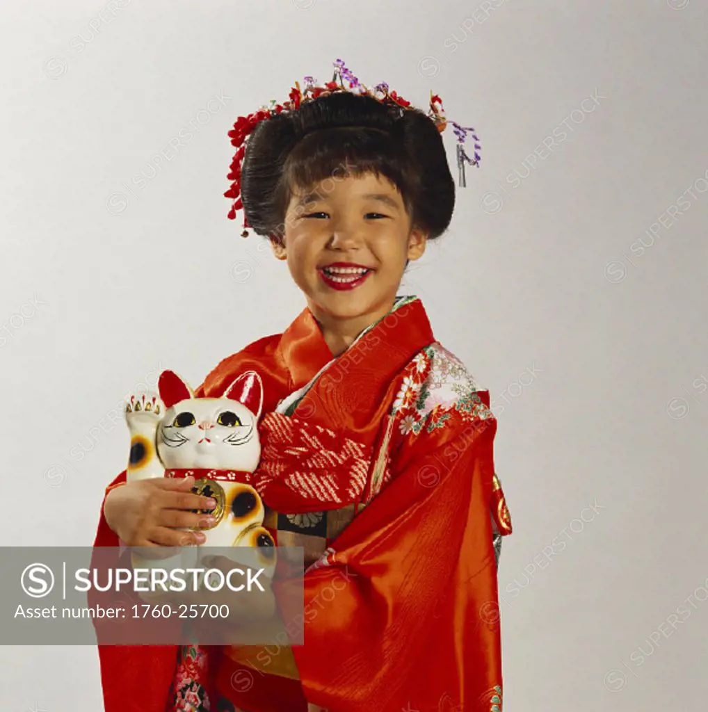 Smiling Japanese girl in red kimono, holding ceramic cat.