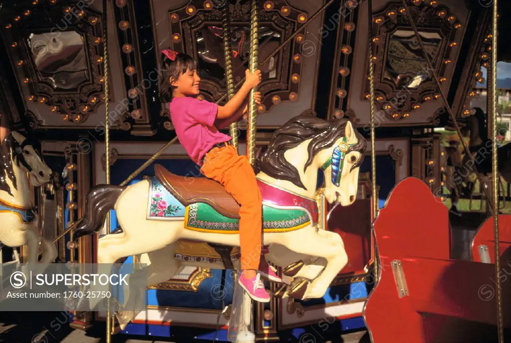 Young girl riding a horse on the carousel, bright colors