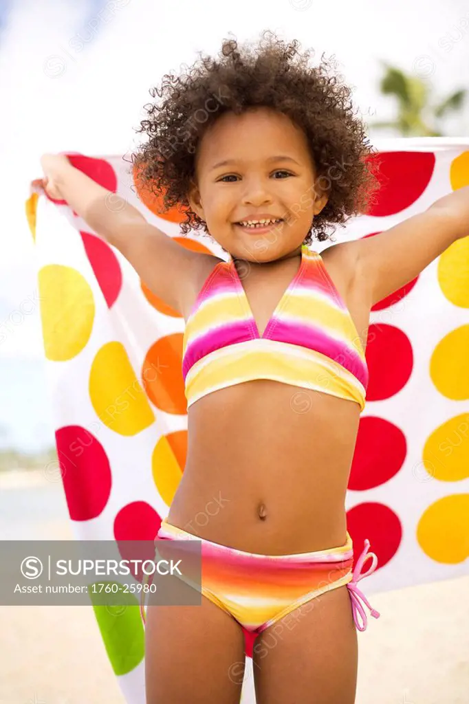 Hawaii, Oahu, Adorable little girl holding a polka_dot towel along the waters edge.