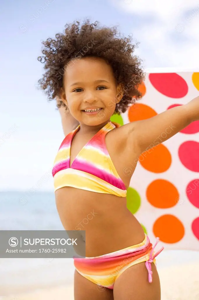 Hawaii, Oahu, Adorable little girl holding a polka_dot towel along the waters edge.