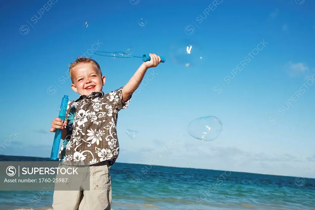 Hawaii, Oahu, Adorable little boy with an aloha shirt playing with bubbles.