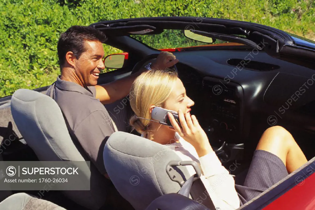 Couple in convertible, girl on mobile phone